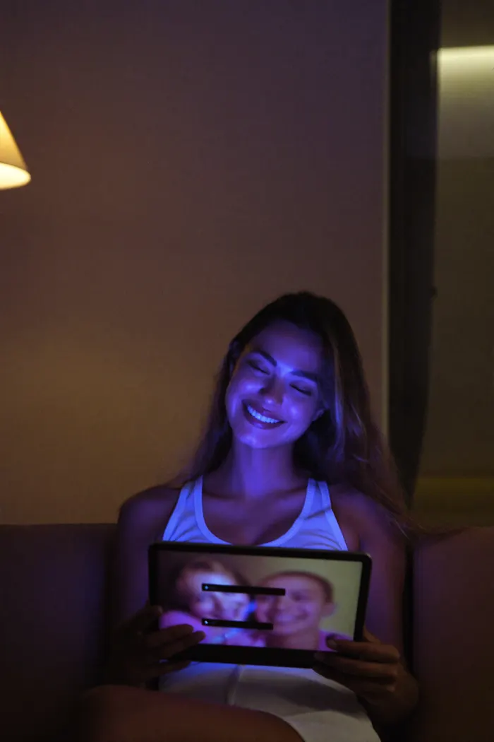 Person watching a live video chat at night, lit by the tablet screen